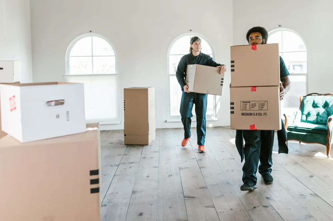 Umzugshelfer tragen Kartons aus einer Wohnung